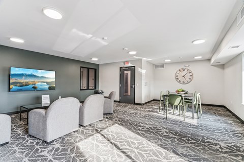 A spacious room with a television, chairs, and a dining table.