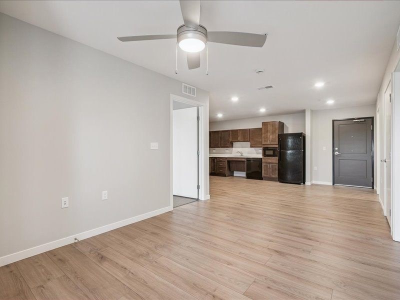 A room with a ceiling fan and wooden flooring.