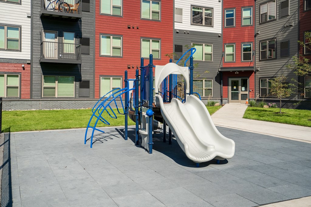 a playground with a slide in front of an apartment building