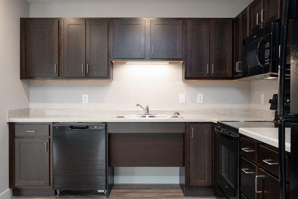 an empty kitchen with dark wood cabinets and a sink