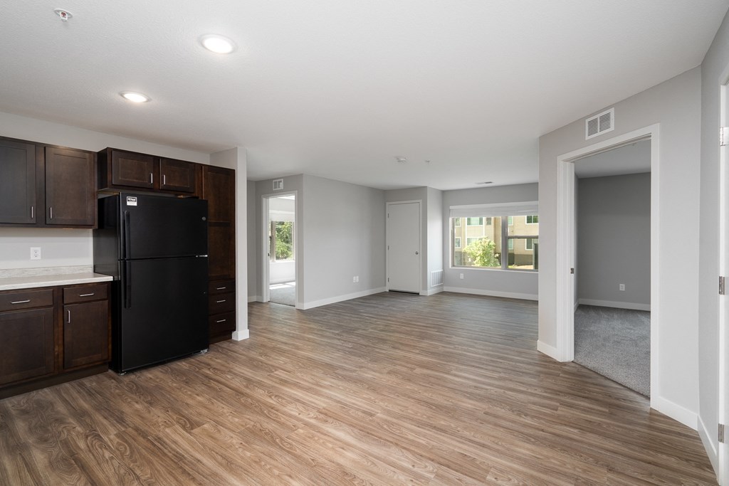 an empty kitchen and living room with a black refrigerator