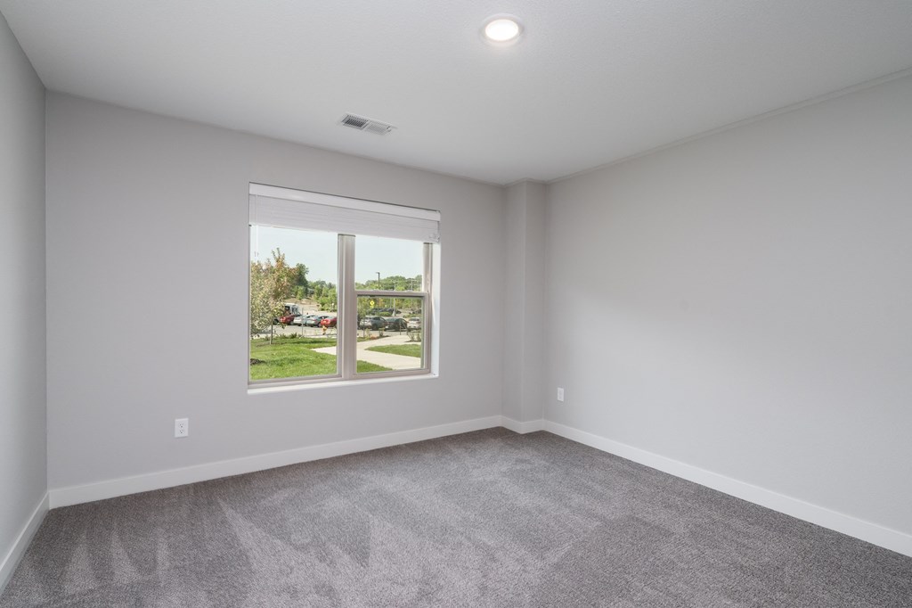 an empty living room with a window and carpet