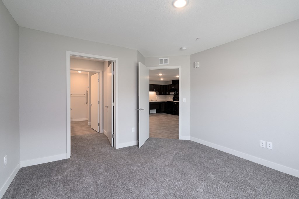 an empty living room with a hallway to a bedroom and a bathroom
