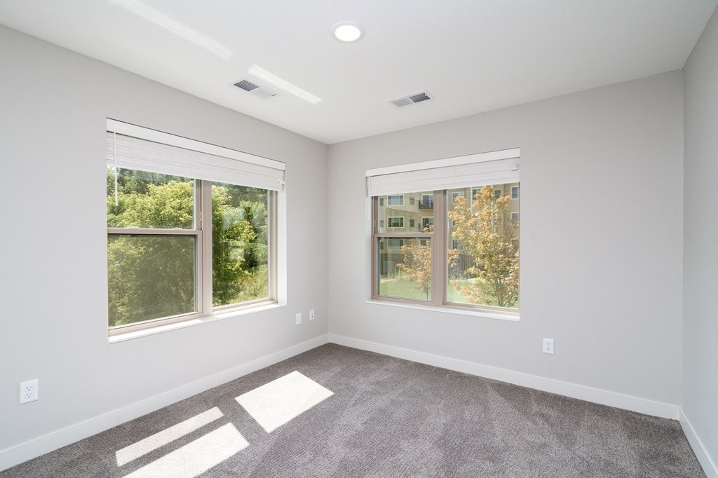 an empty room with three windows and a carpeted floor