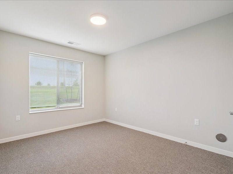 A room with a window and carpeted floor.