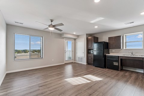 A spacious kitchen with dark wood cabinets and a black refrigerator.