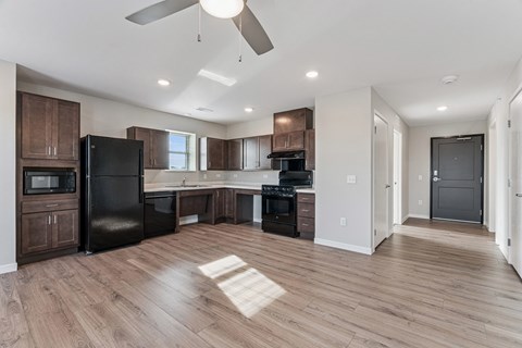 A modern kitchen with dark wood cabinets and a black refrigerator.