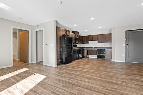 a kitchen and living room with wood flooring and a black refrigerator