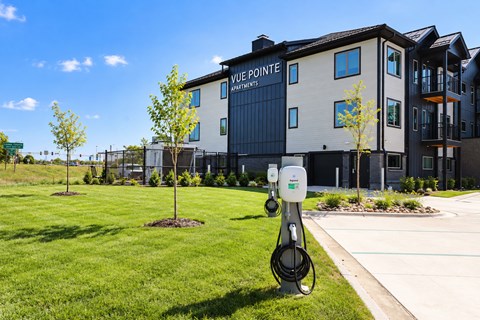 A charging station for electric vehicles is in front of a building with the sign "Vue Pointe Apartments.".