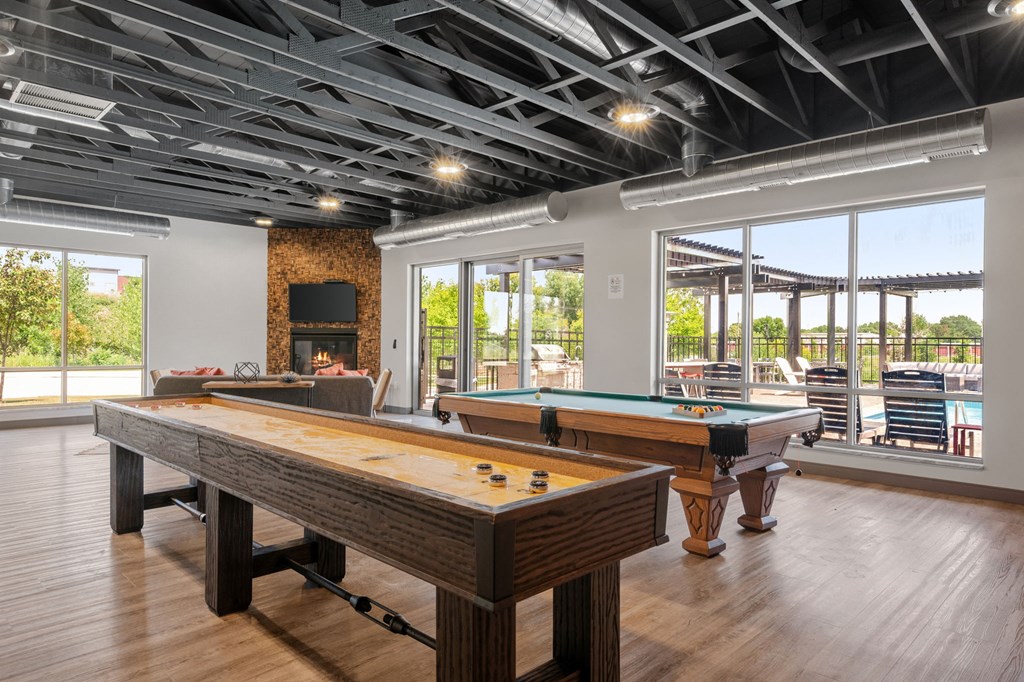 a game room with shuffle board, pool table, and fireplace at TRIO @ Southbridge apartments