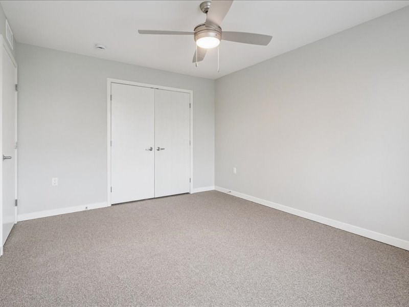 A room with a ceiling fan and carpeted floor.