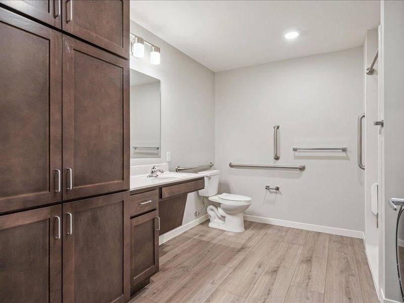 A bathroom with brown cabinets and a white toilet.