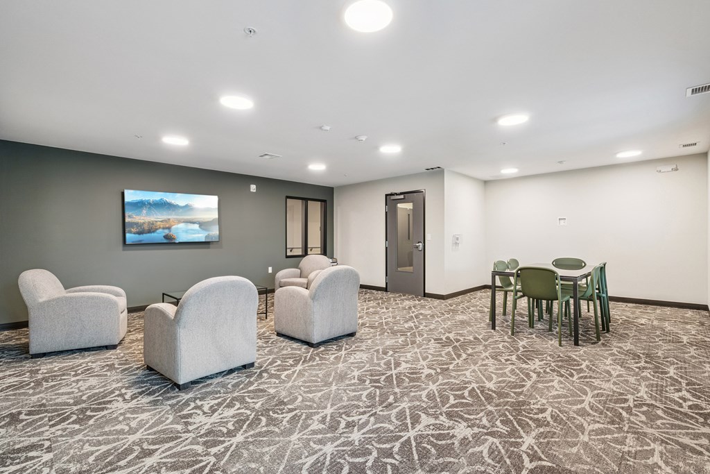 A room with grey carpet and white chairs.