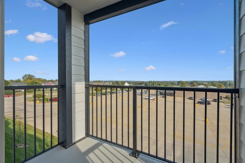 A balcony with a black railing overlooks a parking lot.