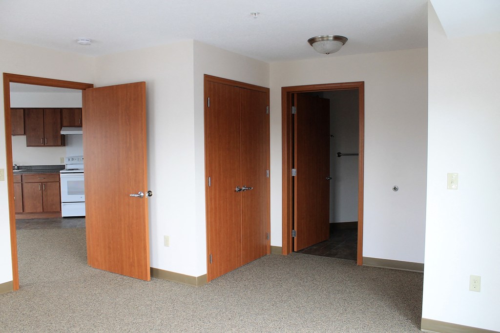 A room with a carpeted floor and two wooden doors.
