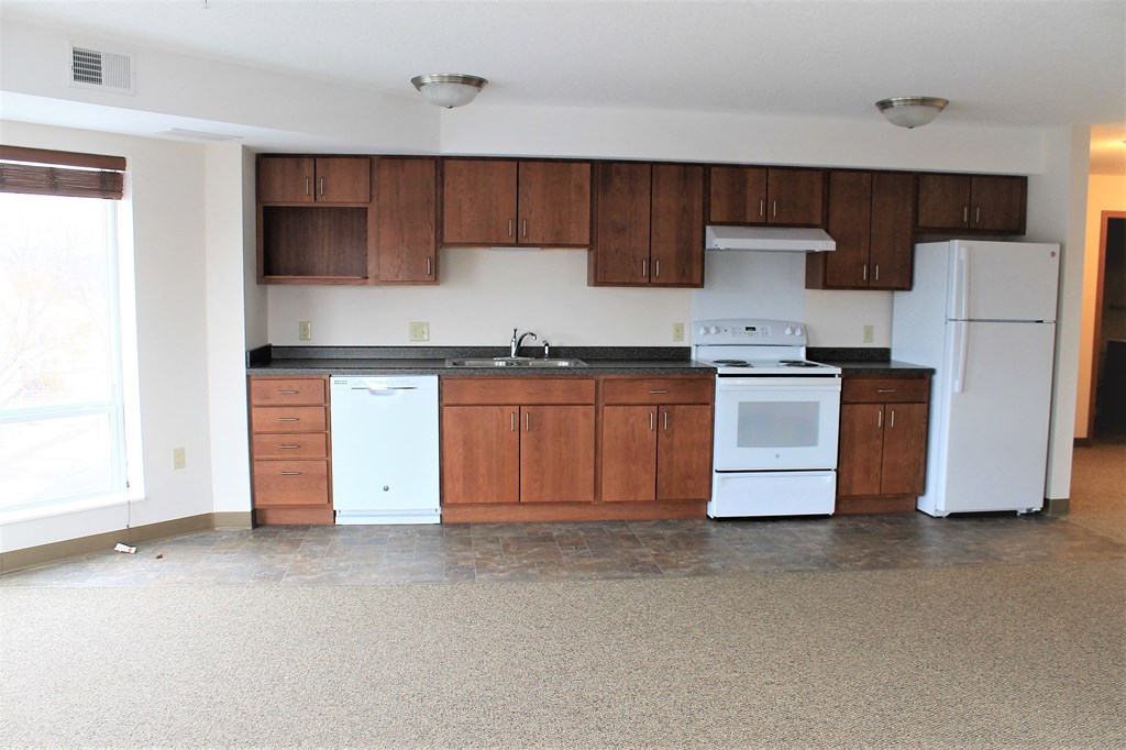 A kitchen with white appliances and brown cabinets.