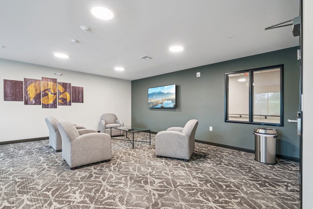 A waiting room with a TV on the wall and comfortable chairs.