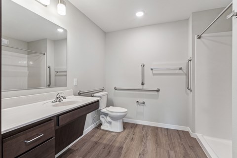 A white bathroom with a toilet, sink, and a walk-in shower.