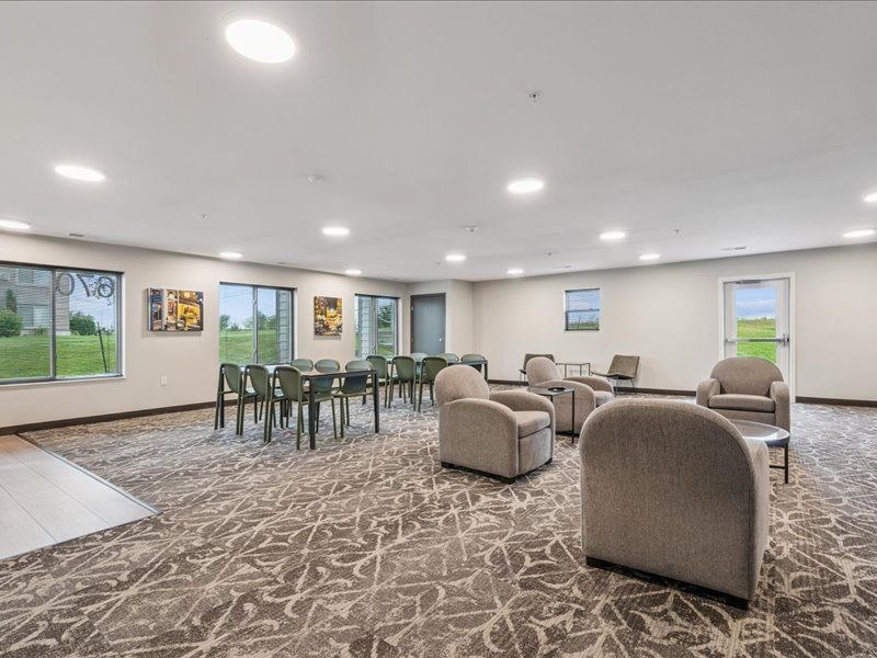 A spacious room with a carpeted floor and a variety of seating options.