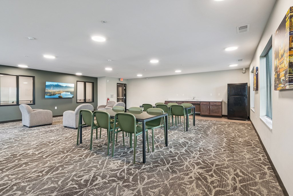 A conference room with a carpeted floor and a large table surrounded by chairs.