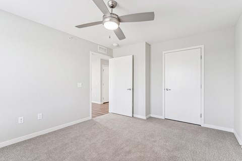 A room with a ceiling fan and carpeted floor.