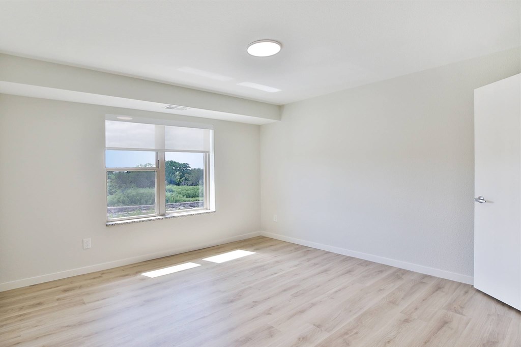 A room with a window and wooden flooring.