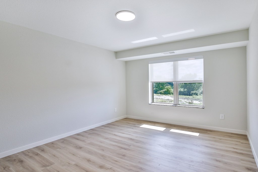 A room with a window and a wooden floor.