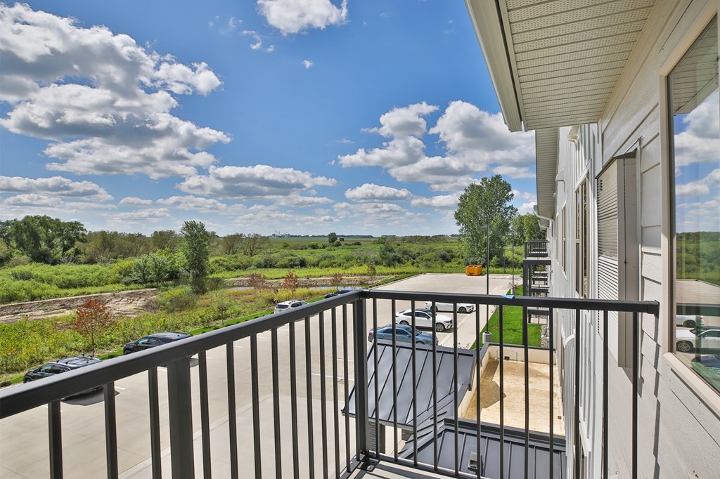 A balcony with a view of a field and trees.