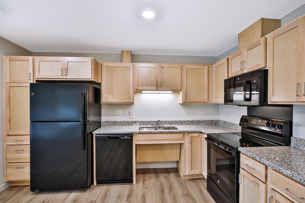 A kitchen with black appliances and wooden cabinets.