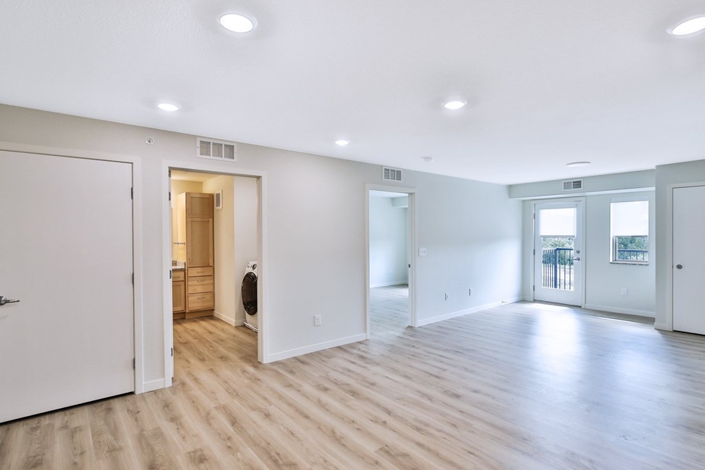 A spacious room with wooden flooring and white walls.