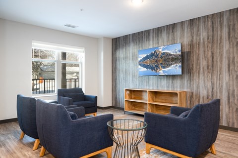 A living room with blue chairs and a wooden wall.