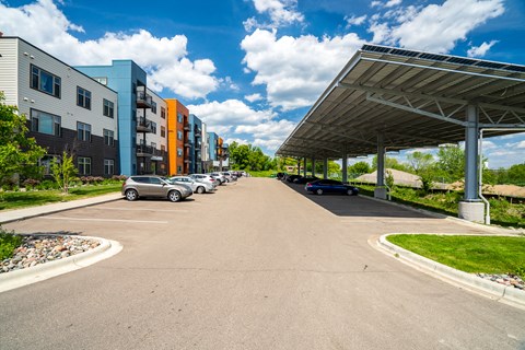 an empty parking lot with buildings on either side and a blue sky with clouds