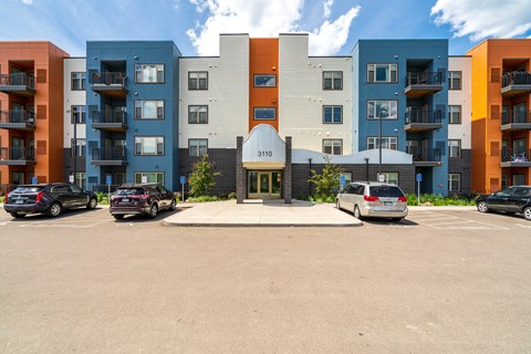 an exterior view of an apartment building with a parking lot