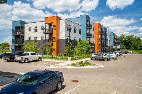 a parking lot with cars in front of an apartment building