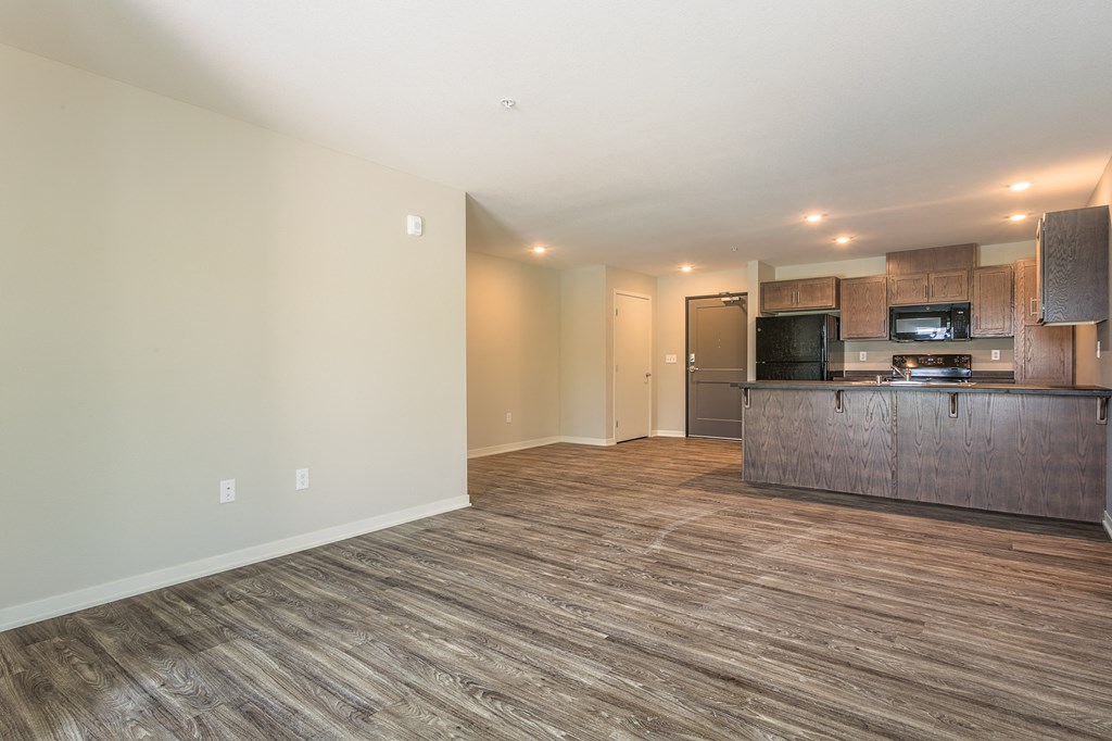 an empty living room and kitchen with a wood floor