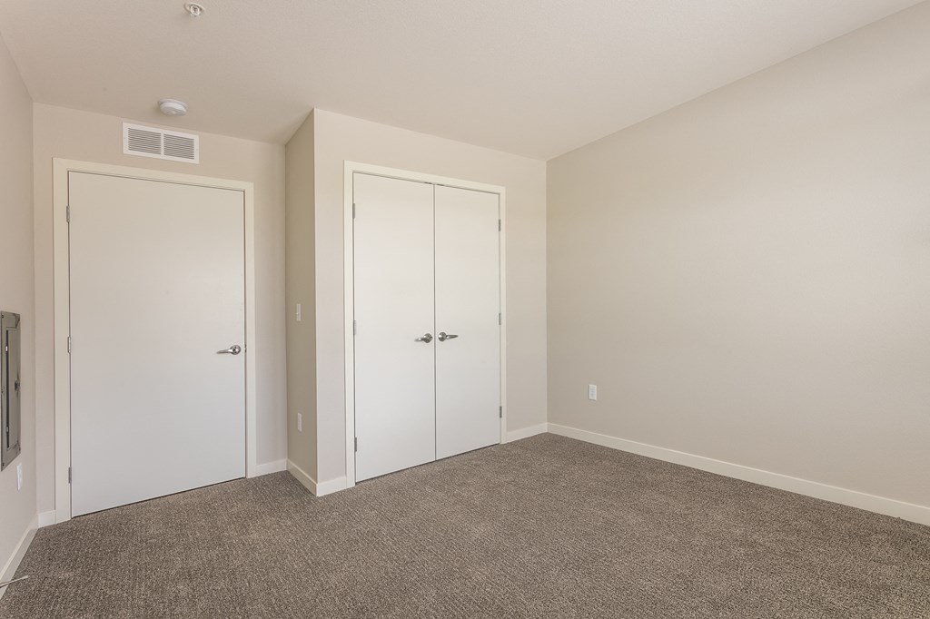 a bedroom with two doors and a carpeted floor