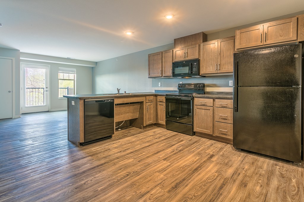 an empty kitchen with stainless steel appliances and wooden cabinets