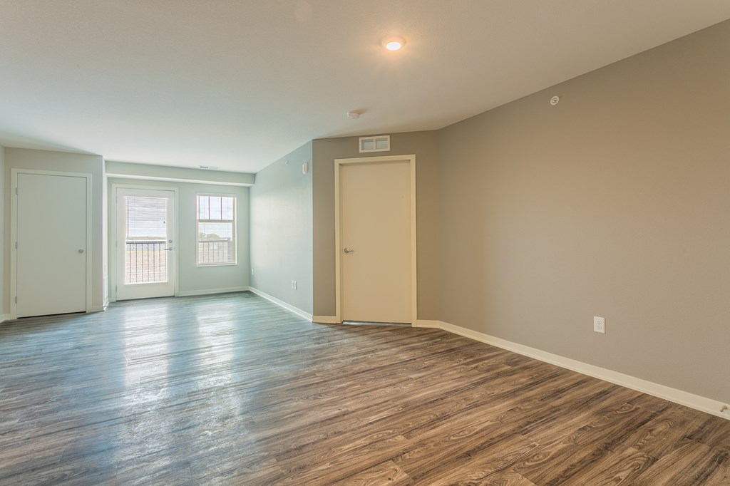 an empty living room with wood flooring and a door