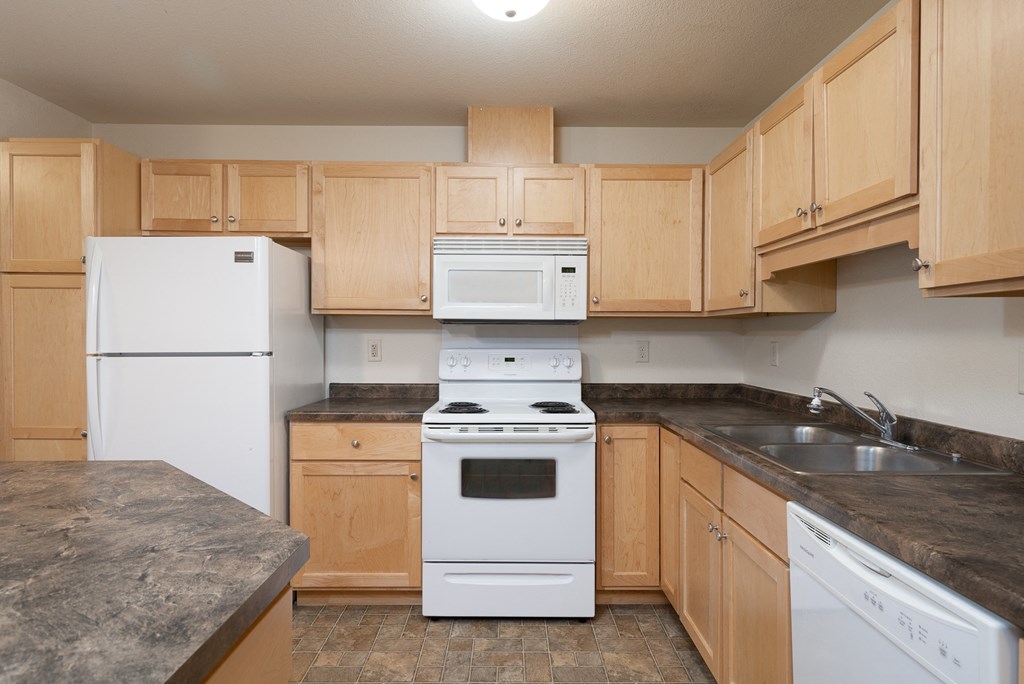 an empty kitchen with wooden cabinets and white appliances