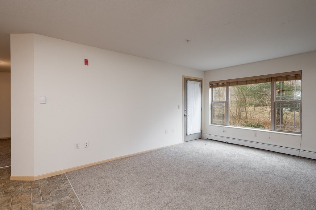 an empty living room with a large window and white walls
