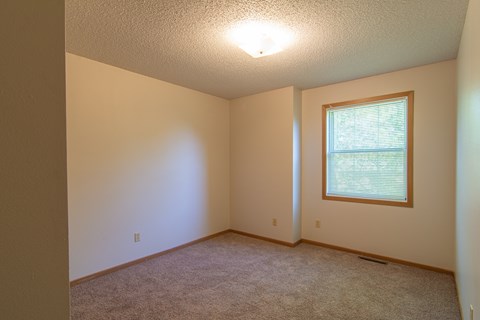 A room with a window and carpeted floor.