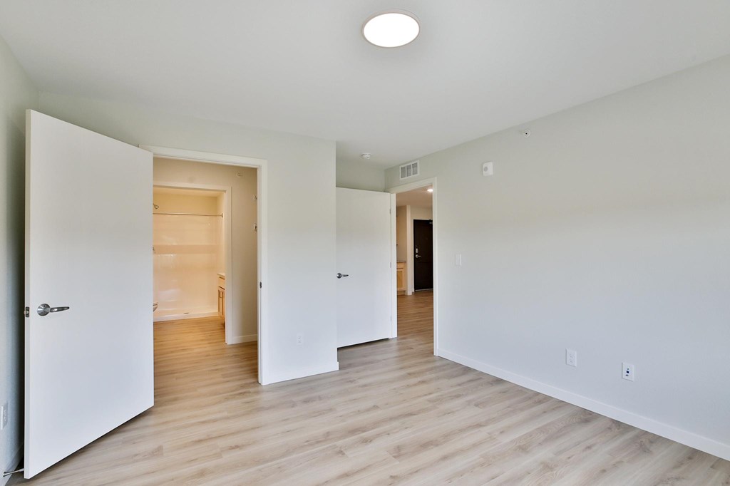 A white room with a light on the ceiling and a door on the left.