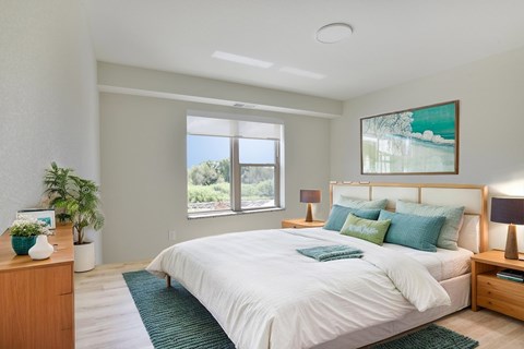 A bedroom with a large bed, a nightstand, and a painting on the wall.