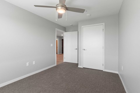 a bedroom with a ceiling fan and a door to a hallway
