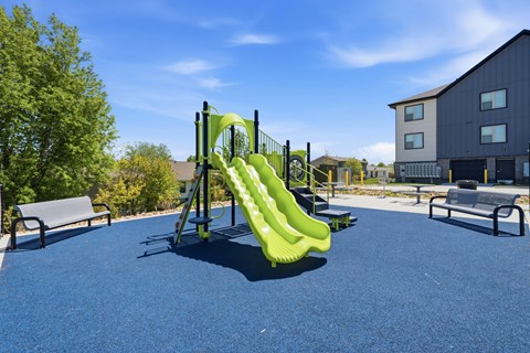 A playground with a green slide and a blue surface.