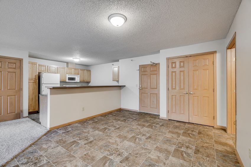 an empty living room with a kitchen with a counter top and a door