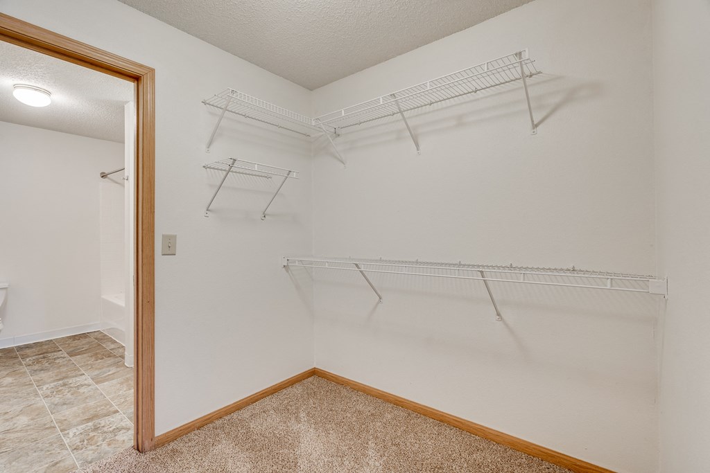 the spacious closet in the bedroom of a rental home with hanging racks on the wall