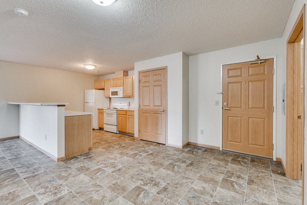 the living room and kitchen of an empty house with a door open
