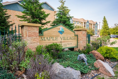 A sign that says Maple Village in front of a building.