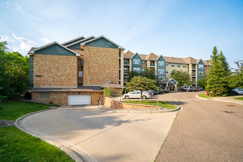 A building with a garage is surrounded by a grassy area and other buildings.